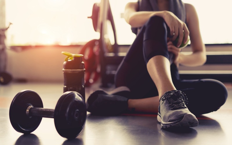 a person sitting in the gym next to a hand weight